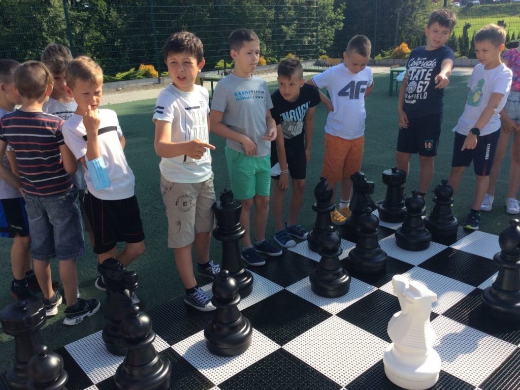 Grupa uczestników grająca szachami ogrodowy w Mystkowie.